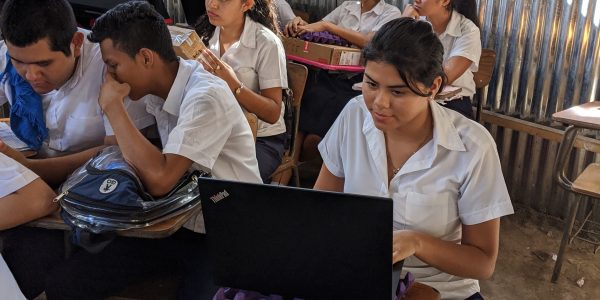 Group of Male And Female Students Sitting In Classroom And Studying On Laptops.